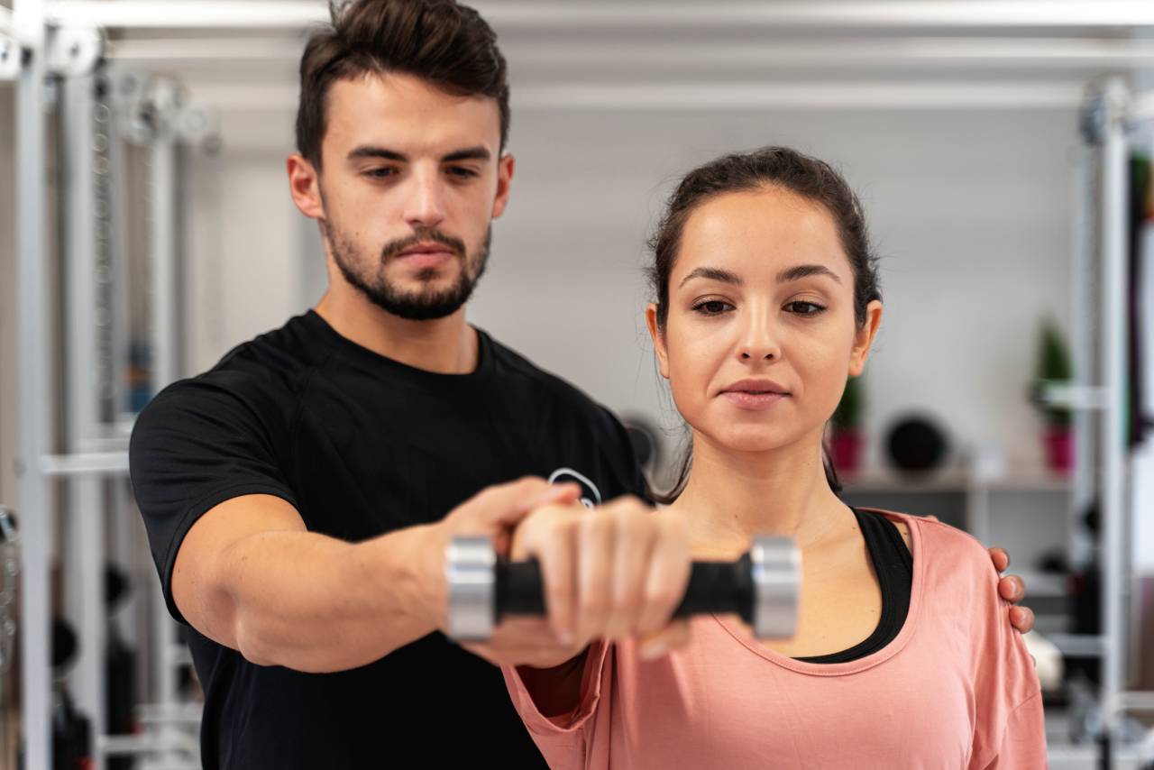 Personal trainer com aluna em academia