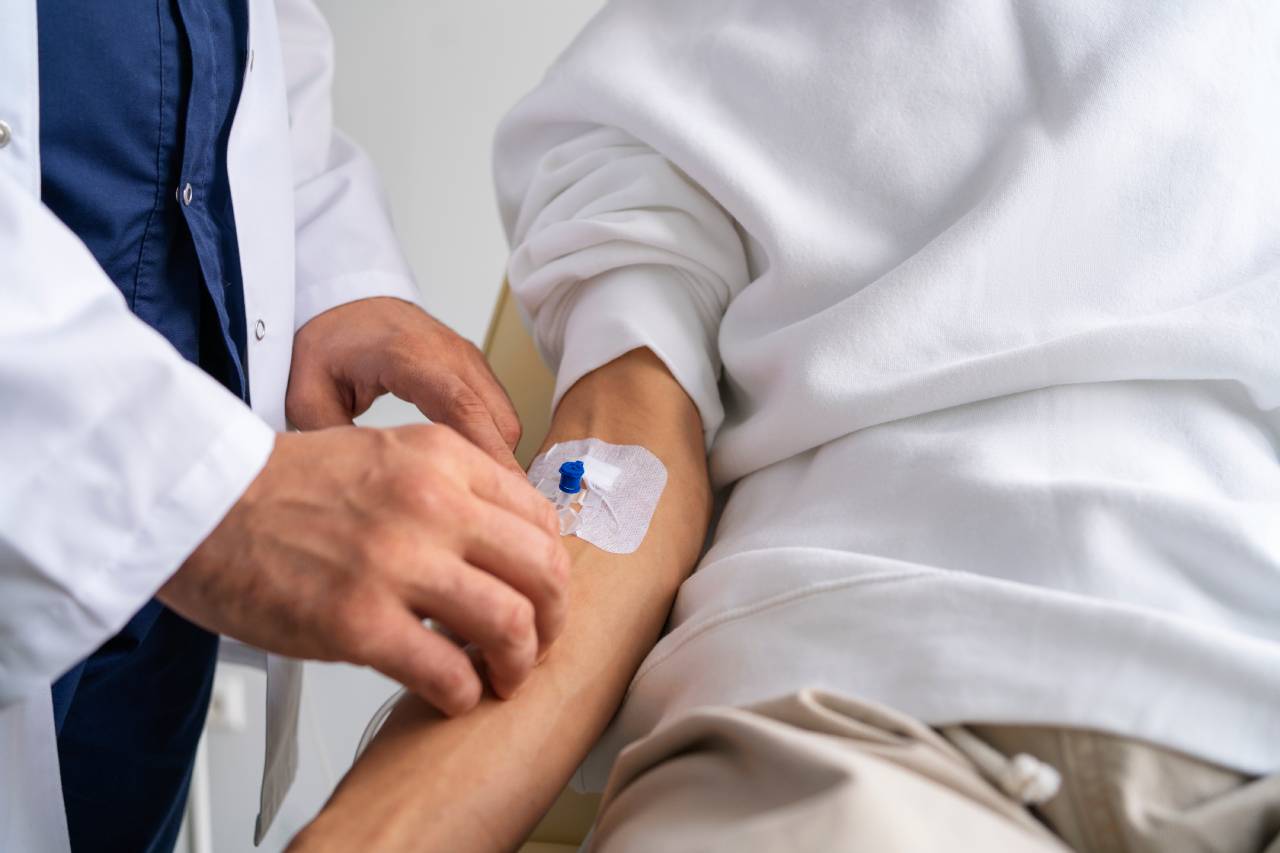 Paciente tendo agulha enfiada no braço