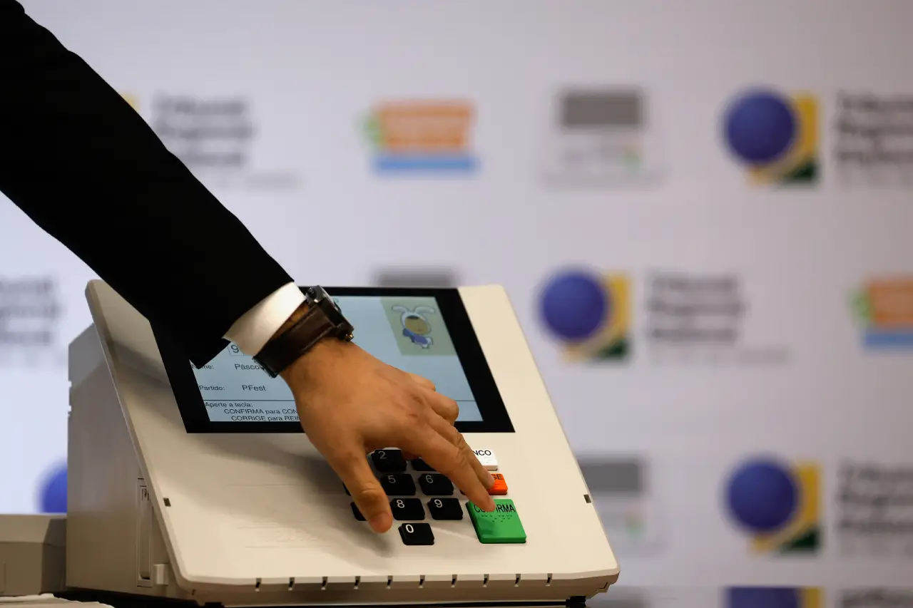 Homem de blazer toca em Urna eletrônica