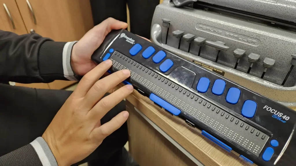 Servidora demonstra Linha braille focus com 40 células de posicionamento do curso e um teclado de 8 pontos. Oferece conexão com até 5 dispositivos simultâneamente.