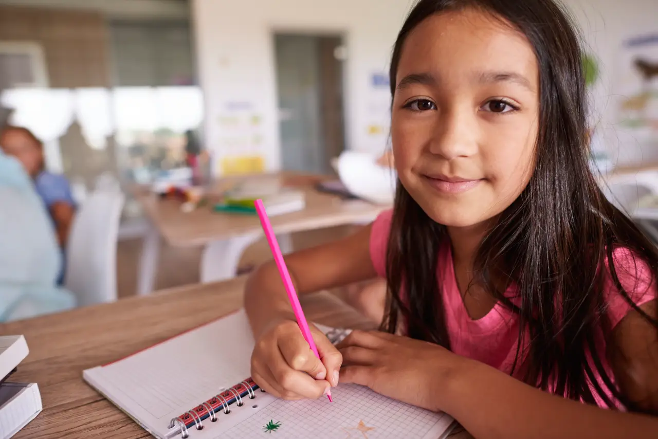 Menina em escola escreve em caderno