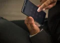 Braço de homem usando paletó digitando telefone