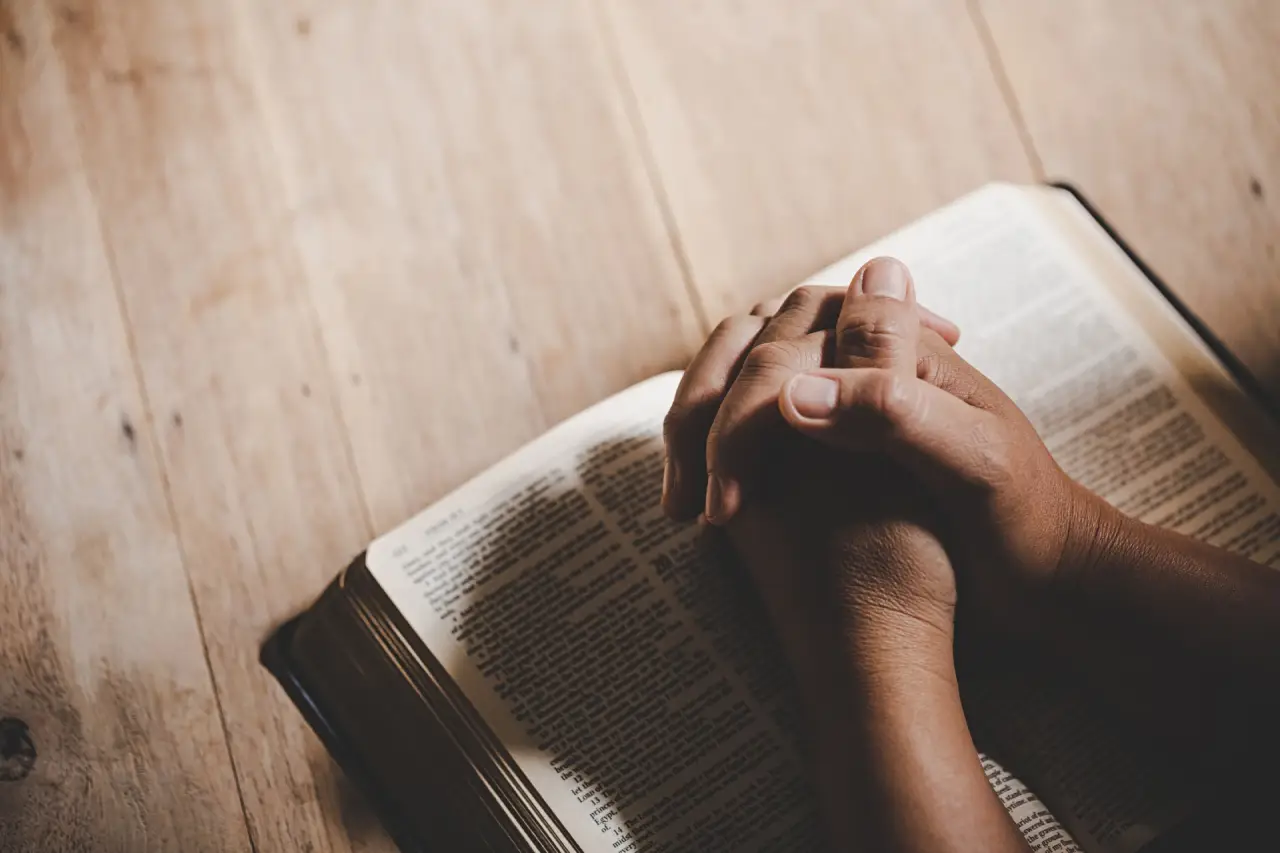 maos-postas-em-oracao-sobre-uma-biblia-sagrada-na-igreja